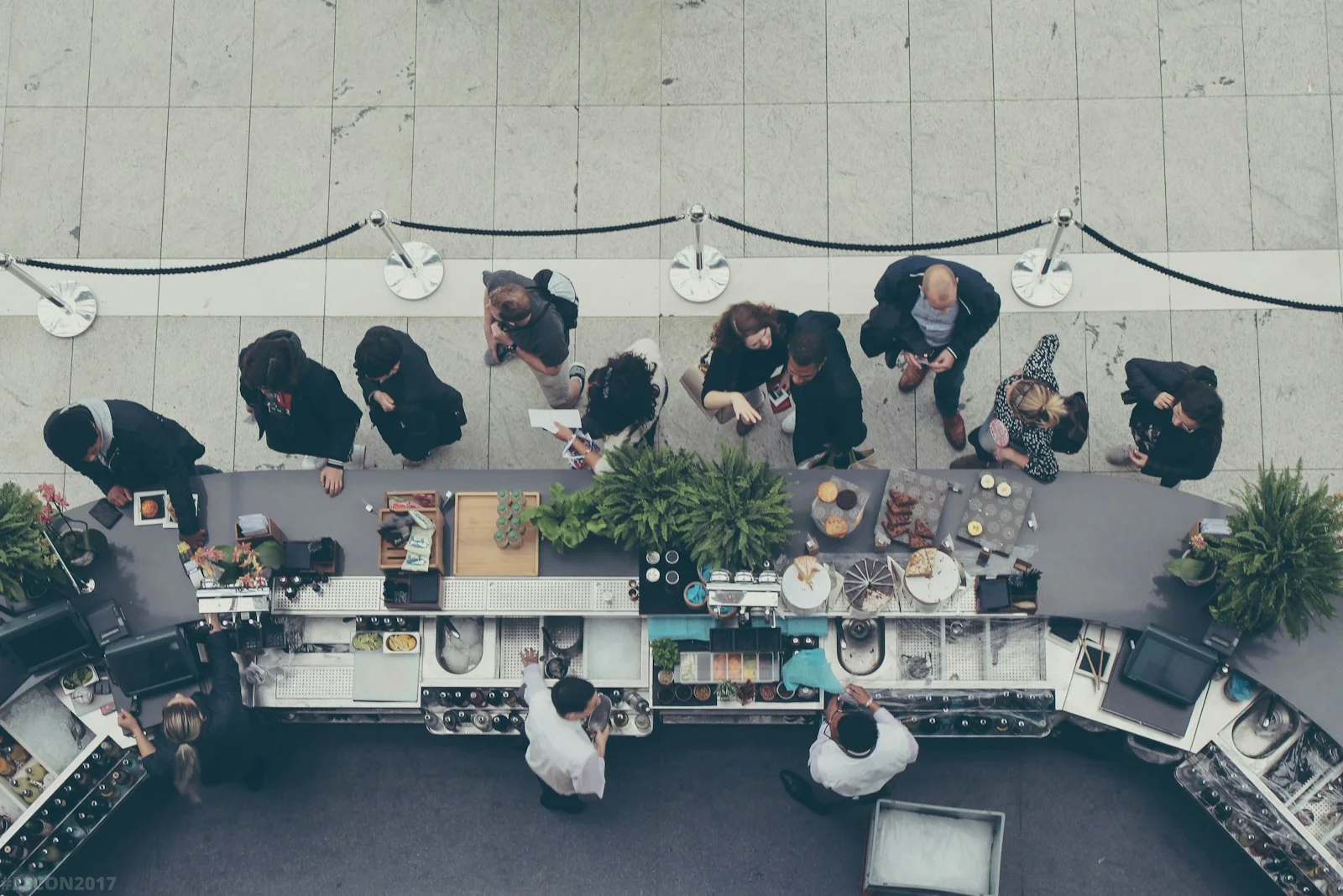 aerial view photography of people lining-up at the food counter - Photo by Michał Parzuchowski on Unsplash Overhead view of customers queuing at a curved café counter while staff serve behind it