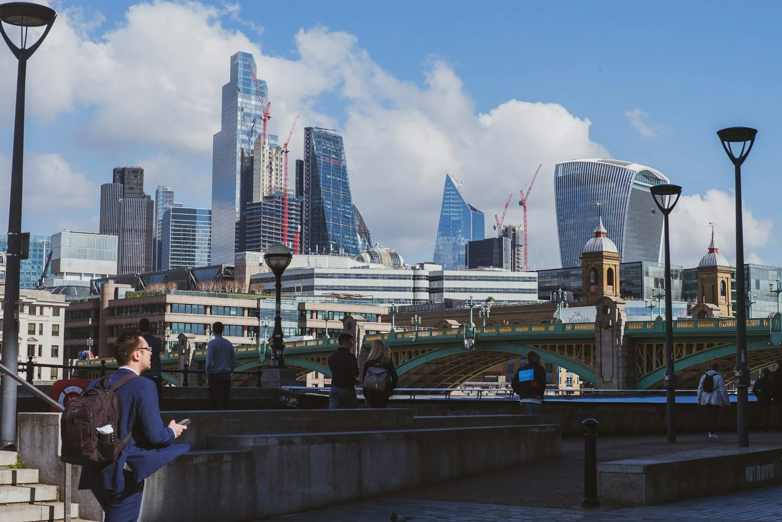 a woman standing on a bridge looking at her cell phone a woman standing on a bridge looking at her cell phone