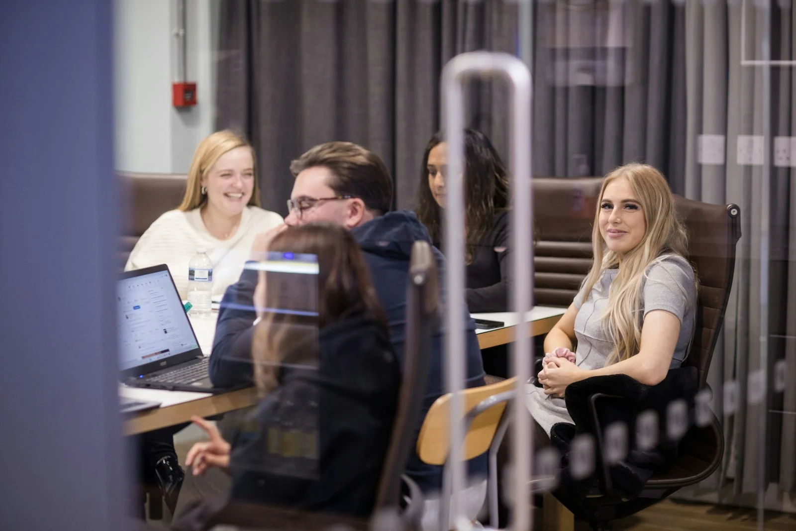 a group of people sitting around a table with laptops a group of people sitting around a table with laptops